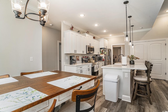 kitchen with appliances with stainless steel finishes, a breakfast bar, a center island with sink, white cabinetry, and dark wood finished floors