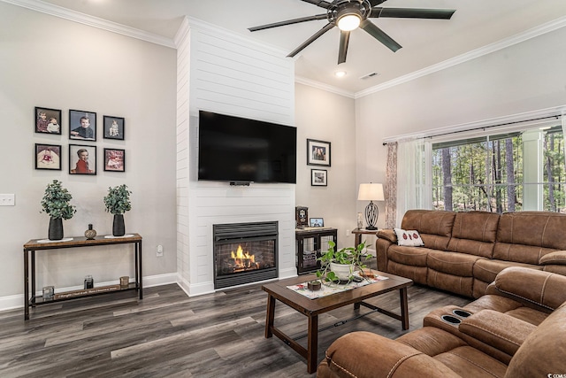 living room with a ceiling fan, dark wood-style floors, baseboards, a large fireplace, and ornamental molding