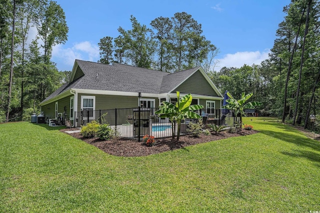 rear view of house featuring roof with shingles, a yard, a patio, and a wooden deck