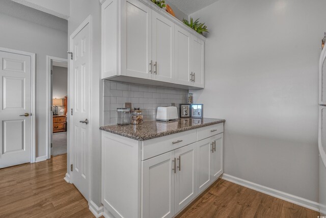 4450 Turtle Ln Unit 2-A, Little River, SC 29566 - kitchen featuring light wood-style flooring, tasteful backsplash, baseboards, white cabinets, and dark stone countertops