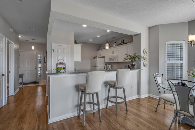 4450 Turtle Ln Unit 2-A, Little River, SC 29566 - kitchen with white appliances, a peninsula, white cabinets, dark wood-type flooring, and a textured ceiling