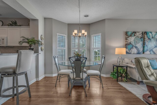 4450 Turtle Ln Unit 2-A, Little River, SC 29566 - dining room featuring wood finished floors, a chandelier, a textured ceiling, and baseboards