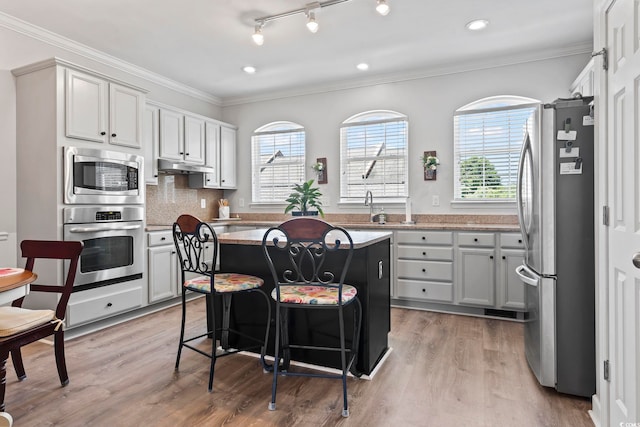 815 Murray Ave, Myrtle Beach, SC 29577 - kitchen with appliances with stainless steel finishes, light wood-type flooring, a center island, a sink, and ornamental molding