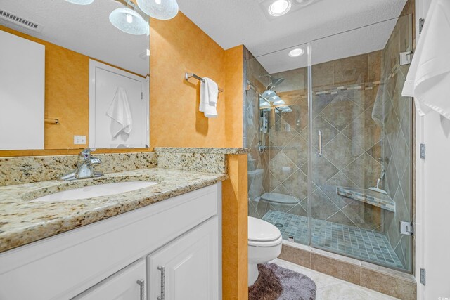 bathroom featuring toilet, a stall shower, tile patterned floors, vanity, and recessed lighting