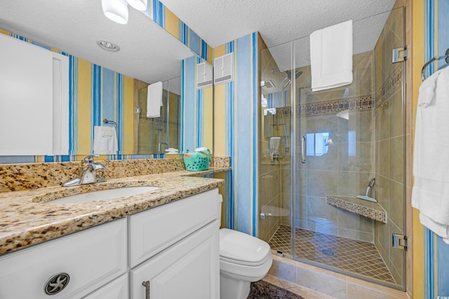 bathroom featuring a textured ceiling, toilet, a shower stall, and vanity