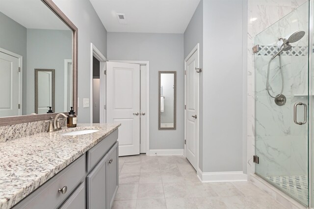 full bathroom featuring a marble finish shower, vanity, and baseboards