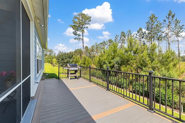 deck with a grill and view of wooded area