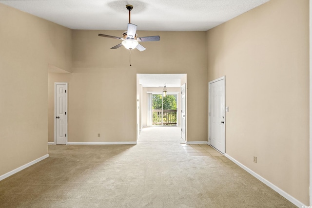 unfurnished room with high vaulted ceiling, light colored carpet, ceiling fan, and baseboards