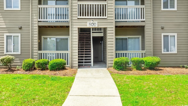 doorway to property featuring a lawn and a balcony