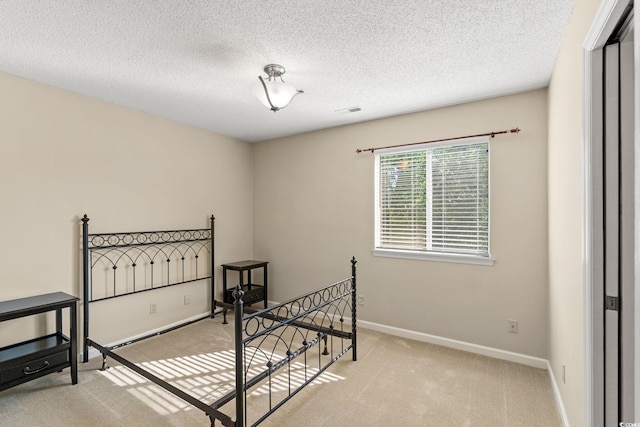 bedroom with light colored carpet, baseboards, and a textured ceiling