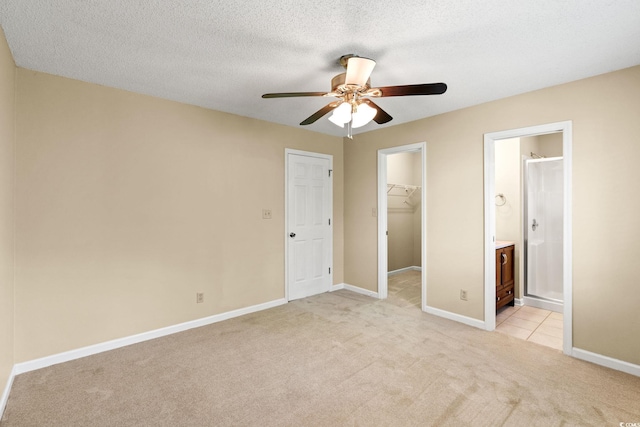 unfurnished bedroom with light colored carpet, a spacious closet, a closet, and baseboards
