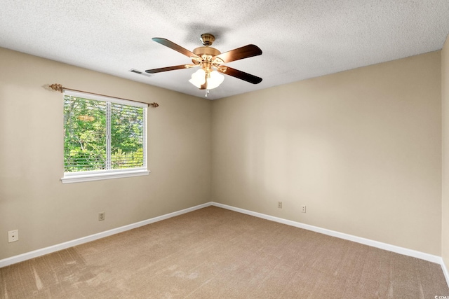 spare room featuring light colored carpet, ceiling fan, baseboards, and a textured ceiling
