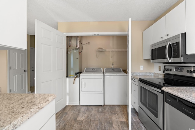 kitchen featuring stainless steel appliances, washing machine and dryer, light wood-type flooring, light countertops, and a textured ceiling
