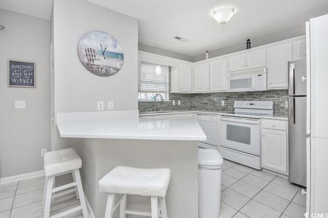 404 1st Ave N Unit H, North Myrtle Beach, SC 29582 - kitchen featuring white appliances, a peninsula, light tile patterned floors, and a sink