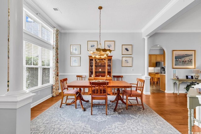 67 Camden Cir, Pawleys Island, SC 29585 - dining area featuring ornate columns, wood finished floors, crown molding, arched walkways, and a chandelier