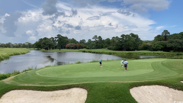 view of community with a water view, view of golf course, and view of scattered trees