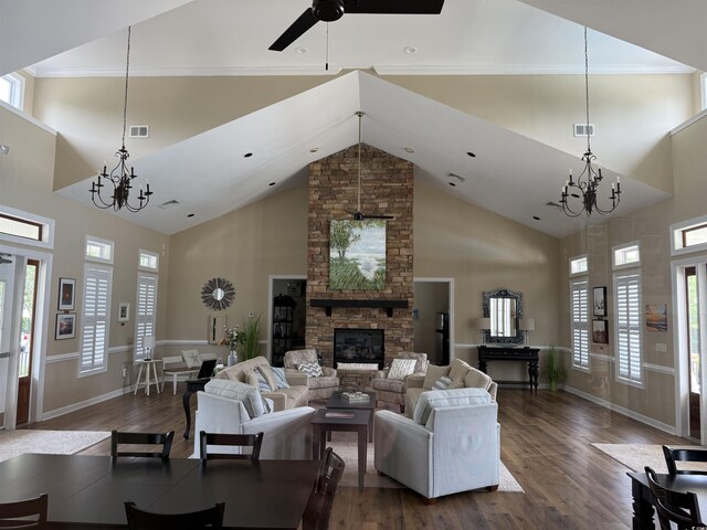 living area featuring a chandelier, dark wood finished floors, high vaulted ceiling, a stone fireplace, and a ceiling fan