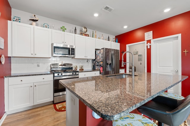348 Hidden Cove Dr, Little River, SC 29566 - kitchen featuring stainless steel appliances, a sink, light wood-style floors, a breakfast bar, and white cabinets