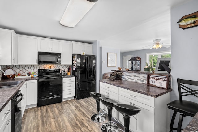 kitchen featuring black appliances, a sink, decorative backsplash, white cabinets, and ceiling fan