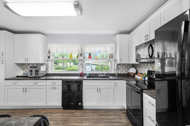kitchen featuring black appliances, a sink, dark countertops, backsplash, and white cabinets