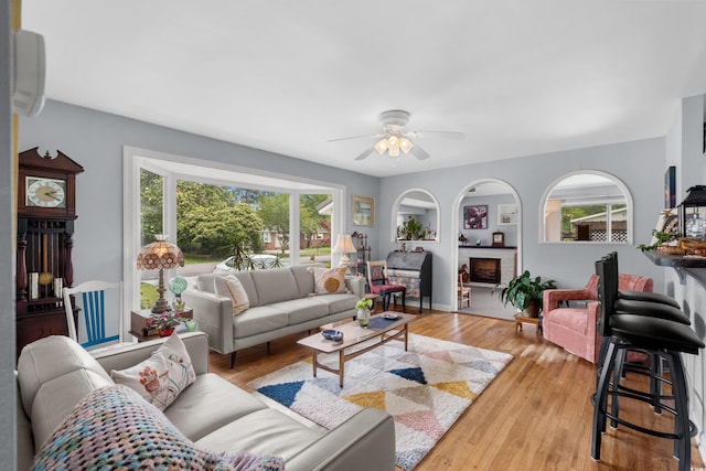 living area featuring a ceiling fan, light wood-style floors, a wall mounted AC, and a fireplace