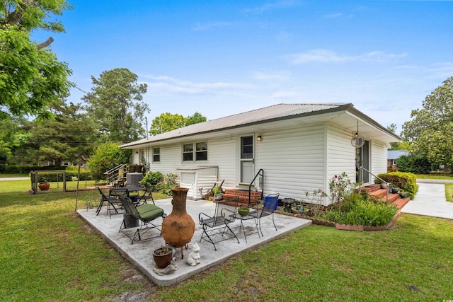 back of property featuring entry steps, a yard, metal roof, and a patio area