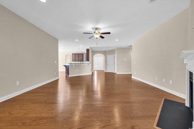 644 Harbor Bay Dr, Murrells Inlet, SC 29576 - unfurnished living room with ceiling fan, a fireplace with flush hearth, arched walkways, baseboards, and wood finished floors