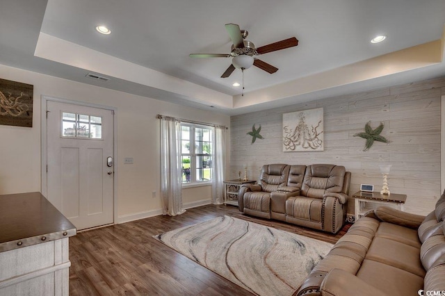 living room featuring a raised ceiling, a ceiling fan, baseboards, recessed lighting, and wood finished floors