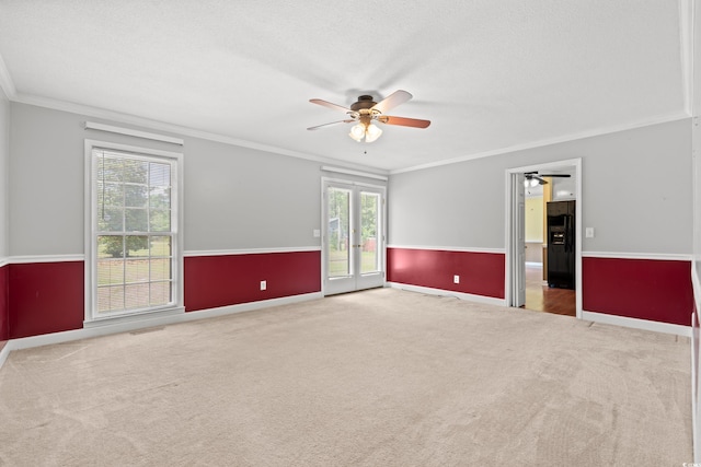 spare room with ceiling fan, carpet, crown molding, baseboards, and french doors