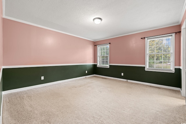 carpeted spare room with crown molding, a textured ceiling, and baseboards