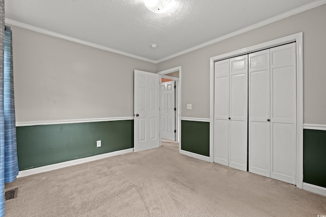 unfurnished bedroom with carpet floors, crown molding, baseboards, a textured ceiling, and a closet