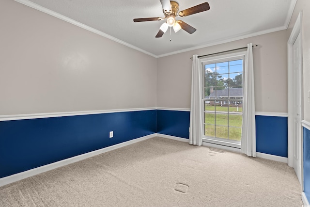 empty room with carpet floors, crown molding, ceiling fan, and baseboards