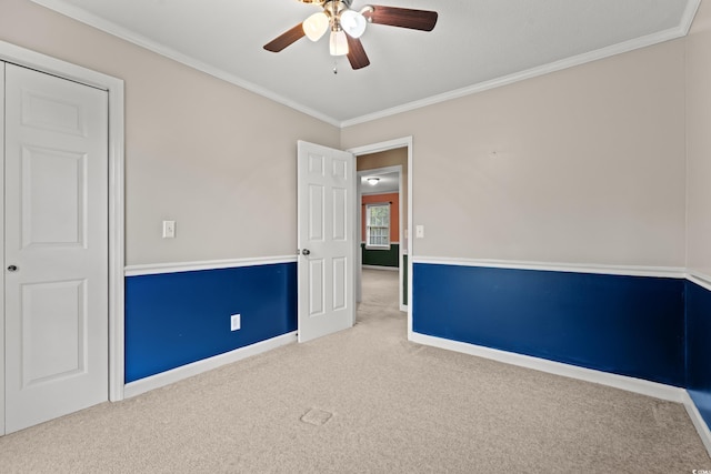 unfurnished bedroom with carpet, ornamental molding, baseboards, and a ceiling fan