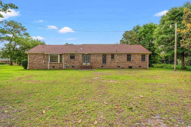 back of house with crawl space, entry steps, a lawn, and brick siding