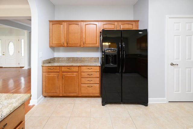 249 Ashepoo Creek Dr, Myrtle Beach, SC 29579 - kitchen featuring black fridge, arched walkways, brown cabinets, baseboards, and light stone countertops