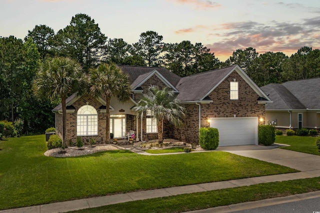 view of front of house with concrete driveway, brick siding, a lawn, and an attached garage