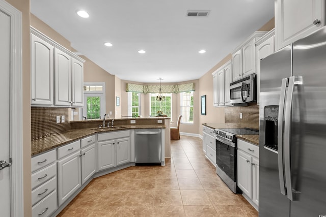 kitchen with appliances with stainless steel finishes, a sink, decorative backsplash, a peninsula, and recessed lighting