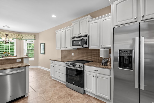 kitchen featuring appliances with stainless steel finishes, white cabinetry, backsplash, baseboards, and a chandelier