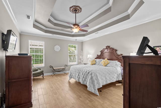 bedroom with a raised ceiling, light wood-style floors, ornamental molding, baseboards, and a ceiling fan