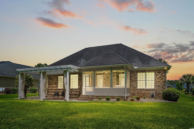 back of property featuring a pergola, brick siding, a yard, a patio area, and a shingled roof