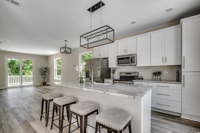 1673 Carriage Ln, Little River, SC 29566 - kitchen with stainless steel appliances, light wood-style flooring, a breakfast bar area, white cabinets, and recessed lighting