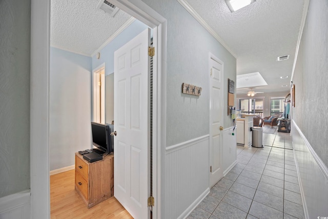 210 N Ocean Blvd Unit 333, North Myrtle Beach, SC 29582 - hallway with a textured ceiling, ornamental molding, a wainscoted wall, and light tile patterned floors