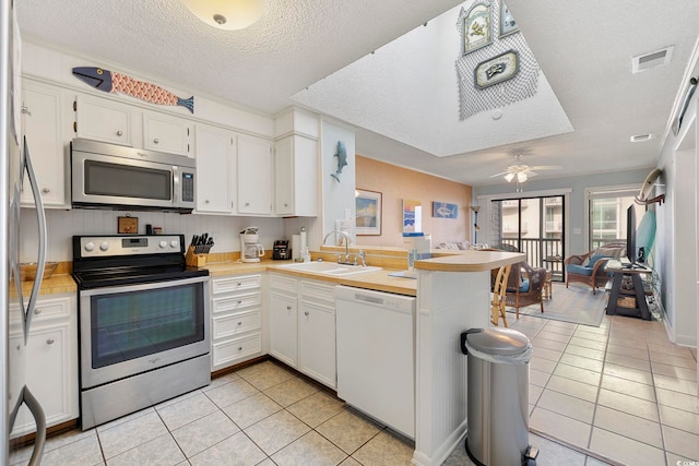 210 N Ocean Blvd Unit 333, North Myrtle Beach, SC 29582 - kitchen featuring appliances with stainless steel finishes, light tile patterned floors, a peninsula, light countertops, and a textured ceiling