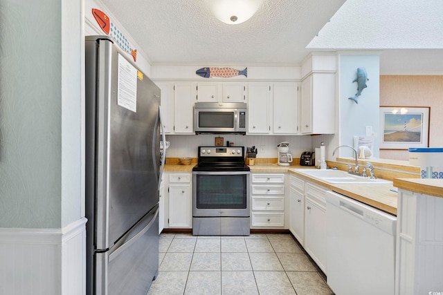 210 N Ocean Blvd Unit 333, North Myrtle Beach, SC 29582 - kitchen with stainless steel appliances, a textured ceiling, light countertops, white cabinetry, and light tile patterned floors