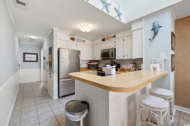 210 N Ocean Blvd Unit 333, North Myrtle Beach, SC 29582 - kitchen featuring appliances with stainless steel finishes, a peninsula, light countertops, white cabinets, and a textured ceiling