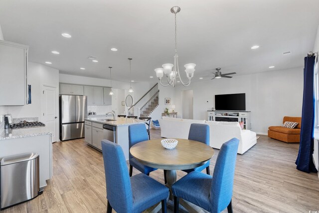 4410 Honir Dr, Myrtle Beach, SC 29579 - dining room featuring light wood finished floors, a ceiling fan, recessed lighting, a chandelier, and stairs