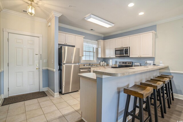 4895 Luster Leaf Cir Unit 302, Myrtle Beach, SC 29577 - kitchen with stainless steel appliances, a peninsula, baseboards, crown molding, and a kitchen breakfast bar