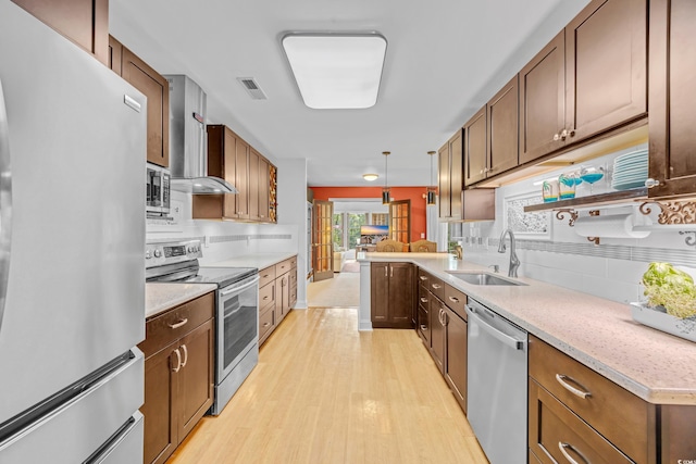 444 Dornoch Dr, Pawleys Island, SC 29585 - kitchen featuring stainless steel appliances, a sink, tasteful backsplash, wall chimney range hood, and light wood-style floors