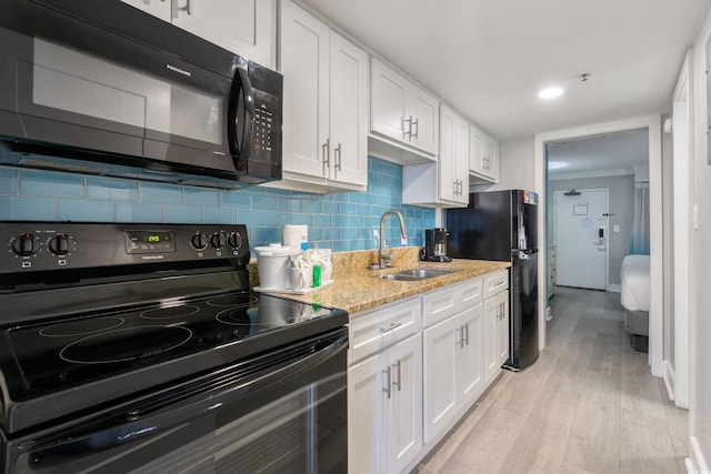 7200 N Ocean Blvd Unit 360, Myrtle Beach, SC 29572 - kitchen with black appliances, a sink, white cabinets, light wood-type flooring, and backsplash