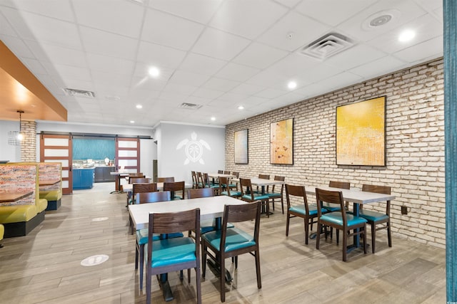 7200 N Ocean Blvd Unit 360, Myrtle Beach, SC 29572 - dining space featuring brick wall, light wood finished floors, and a paneled ceiling